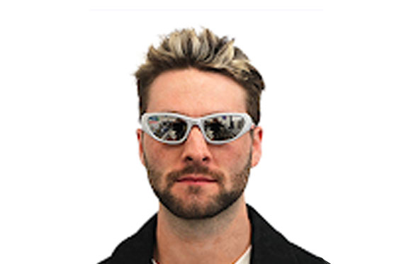 A man with short, blonde-streaked hair and a beard wearing white-framed sunglasses against a white background.