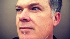 Close-up of a man with short grey hair and blue eyes looking off-camera.