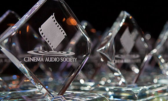 Several diamond-shaped crystal awards with the Cinema Audio Society logo on a reflective surface.