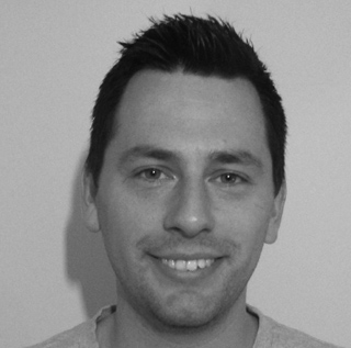 Black and white headshot of a man with short dark hair smiling at the camera.