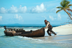 A man in pirate attire pulls a small wooden boat onto a tropical beach with palm trees.