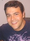 A smiling man with dark hair wearing a dark blue graphic t-shirt.