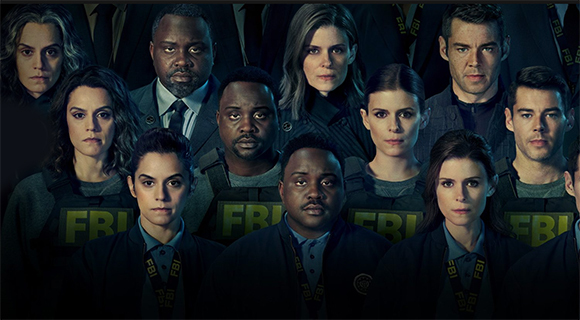 A group of diverse men and women looking intensely at the camera in dark clothing.