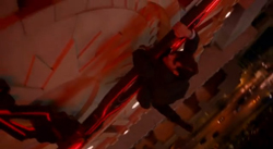 A person in a dark suit climbs a structure illuminated by glowing red lines at night.
