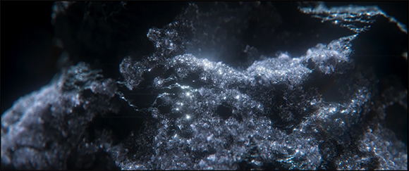Macro view of a dark, textured mineral surface with small, bright glints of light reflecting off crystals.