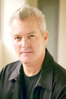 A man with short grey hair and a black jacket looking toward the camera.