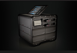 A black modular electronic device with a tilted touchscreen interface and multiple storage compartments.