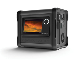 A black RED Digital Cinema Vault media storage device with a screen displaying a sunset.