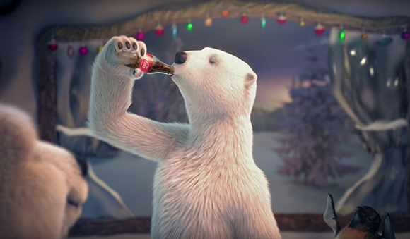 A polar bear holds a glass bottle to its mouth and drinks while looking out a window.