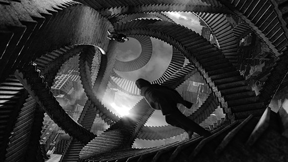 A person falls through a surreal, infinite loop of black staircases overlooking a city in black and white.