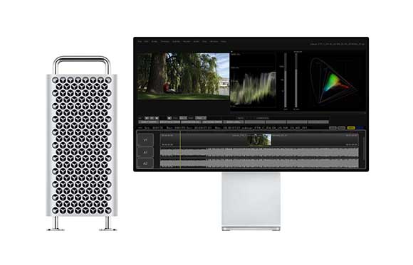 A silver computer tower next to a wide monitor showing a video editing interface with timelines and color tools.