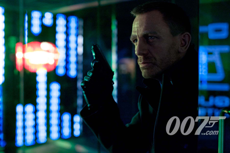 A man in a dark coat holds a handgun up while looking intensely toward the side in a blue and green lit room.