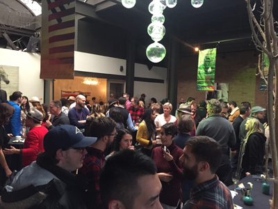 A diverse group of people are gathered indoors at an event, some are talking and others are standing around.