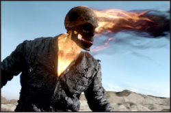 A skeletal figure with a flaming skull wearing a dark, textured jacket under a clear blue sky.
