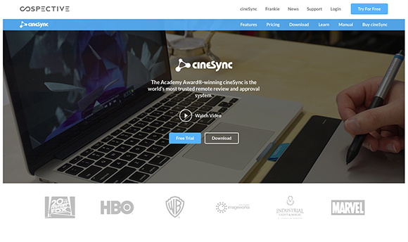 A laptop shows the cineSync website on a wooden desk next to a hand holding a stylus.