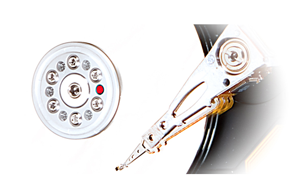 A circular hard drive platter with mounting screws next to a mechanical read/write arm assembly.