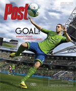 Soccer player in green and blue uniform kicks ball in stadium with crowd.