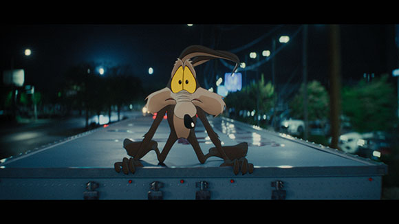 An animated brown cartoon character sits on the edge of a flatbed truck under streetlights at night.