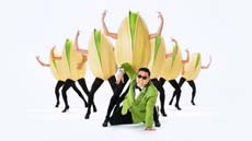 A man in a green suit poses in front of several dancers wearing large corn cob costumes.