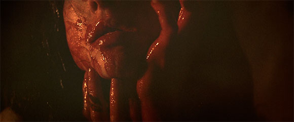 Close-up of a person's face and hands in dim, warm lighting.