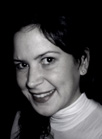 Black and white close-up portrait of a smiling woman wearing a light-colored turtleneck.