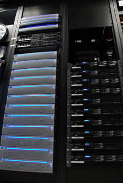 Two black server racks filled with various networking hardware and illuminated blue lights.