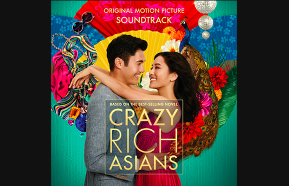 A man and woman embrace against a colorful background with a peacock, flowers, and jewelry.
