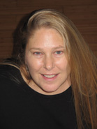 A woman with long blonde hair smiling while wearing a black top.
