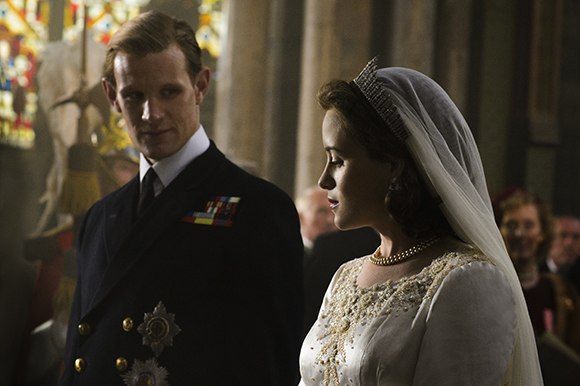 A man in a dark naval uniform stands next to a woman in a white wedding dress and veil.
