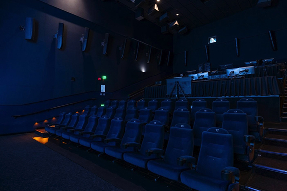 Rows of empty blue velvet seats in a dimly lit movie theater.