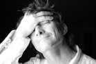 Black and white portrait of a person with eyes closed and hand resting on their forehead.
