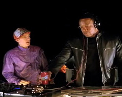 A person in a purple shirt looks at another person wearing headphones and a black leather jacket.