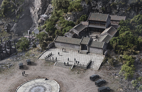 Aerial view of a traditional stone courtyard complex with tiled roofs built into a lush, rocky mountainside.