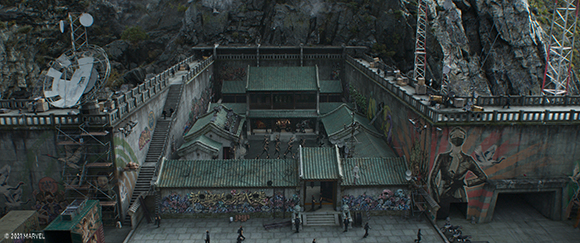 Aerial view of a walled courtyard complex with traditional green-roofed buildings nestled against a cliffside.