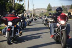 A line of motorcyclists riding on a paved road during the day.