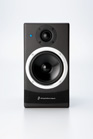 A black rectangular bookshelf speaker with a circular tweeter and a large woofer accented by a white ring.