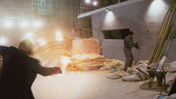 A person in dark clothing reaches toward a bright light amidst construction materials and debris.
