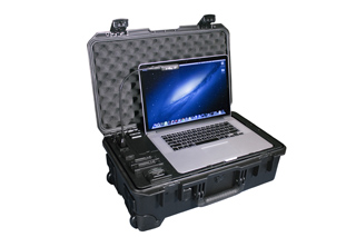 A silver laptop sits open inside a black, ruggedized protective equipment case with foam lining.