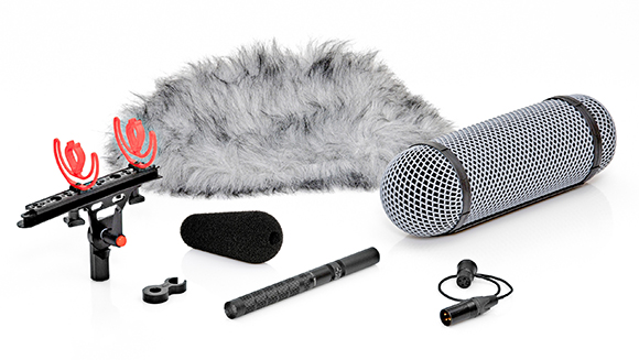 A collection of microphones, wind muffs, and mounting hardware laid out on a white surface.