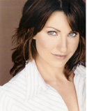 A woman with dark brown hair and blue eyes wearing a white striped shirt.