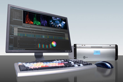 A computer monitor displaying video editing software, a specialized keyboard, a mouse, and a silver hardware device.