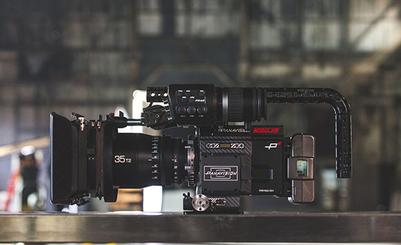 A black Panavision modular cinema camera with a large lens and top-mounted monitor on a dark surface.