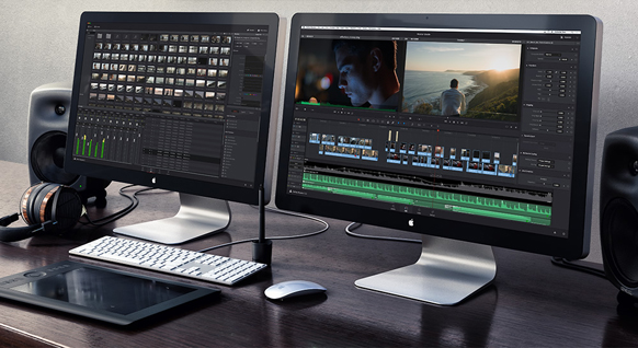 Two computer monitors displaying video editing software, a keyboard, mouse, tablet, and studio speakers on a desk.