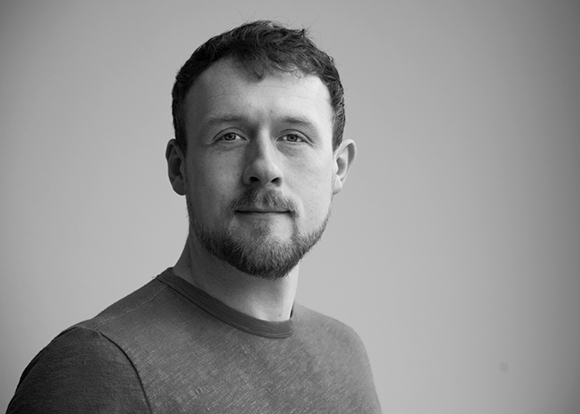 Black and white headshot of a man with short hair and a beard looking toward the camera.
