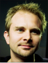 A man with short blond hair and blue eyes looking slightly off-camera.