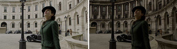 A woman in a green suit and black hat looks up in a curved, stone courtyard with vintage cars.