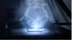 A glowing blue holographic sphere contained within a translucent geometric structure in a dark setting.