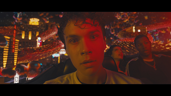 A young man with a shocked expression in a crowded, neon-lit setting with colorful decorations.