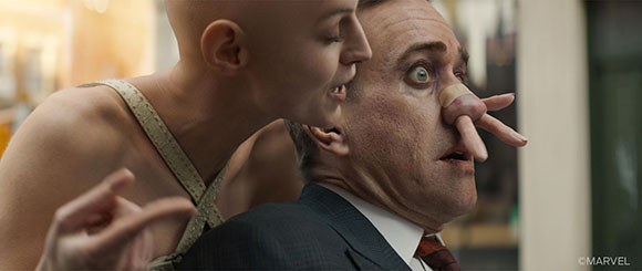 A person with an unnaturally long nose points toward another person's face.