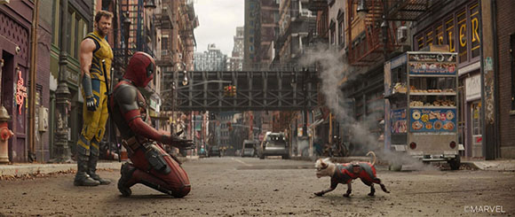 Deadpool kneels in a city street next to a small, patterned dog.